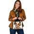 Cute cartoon puppy sits on the ground with its paws spread shoulder handbag