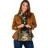 Green frog playing the banjo on top of human skull shoulder handbag