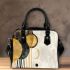 Abstract composition of circles and lines in gold shoulder handbag