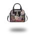 Black and white border collie sits in the foreground amidst blooming flowers shoulder handbag