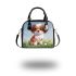 Cute brown and white puppy sits on the grass shoulder handbag